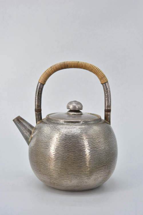 【精品】日本 大正时期 金工世家 一鹤斋 断热把手 纯手工小锤目 底部款识“一鹤斋”性感小炮口 土瓶式精品小银壶 壶盖一体满槌精细的小槌目纹理，宛如粼粼湖水，微波荡漾，兴起层层涟漪。使人流连忘返，无法忘怀，真可谓超凡脱俗的心境品茗之器。 重255g 高15.5cm 容量650cc（一鹤斋以生产纯手工打造银器而闻名，土瓶式的小一鹤银壶实在少见）