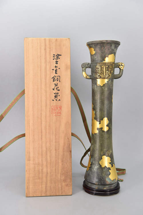 【重器】日本 平安 四世秦藏六  涂金铜 饕餮纹龙耳觚式 大花瓶 共箱  全品 带原箱、箱书，四世藏六，款识清晰。
本件藏六极品重器，线条优美利落，饕餮纹精细，可镇店。

初代藏六：文政七年(1824年)--明治二十三年(1890年)，出生於山城，初名秦米藏，日本幕末、明治时期的金工。少年时在龍文堂学习金工铸造，技艺纯熟后，又深入研究中国古代青铜器文化，作品以大量使用先秦两汉青铜器元素为特点。
初代藏六成为当时日本金工第一人，先后模仿中国青铜器式样，制作江户时期孝明天皇的御用印章、幕府将军德川庆喜的黄金印章，以及明治时期的天皇御玺、日本国玺。
二代藏六（1854-1932）：初代秦藏六的长男；
三代藏六（1882-1944）：二代的三男，京都金属工艺协会名誉会长
四代藏六（1898-1984）：四代是二代的五男，三代的弟弟。昭和十九年(1944年)袭名四代秦藏六；技術保存園資格，京都金属工艺协会会长；昭和五十九年(1984年)殁，享年八十六歲
五代藏六（1927-1998）
六代藏六（1952-    ）